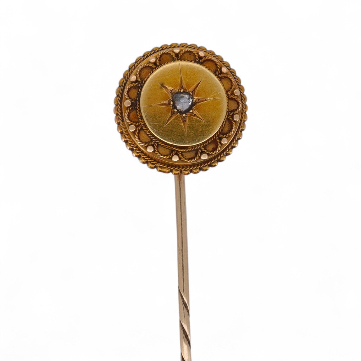 A Victorian gold and diamond stick pin, late 19th century, of circular outline with rope twist and grainti decoration, centring on a rose-cut diamond, length 7cm, gross weight 3 grams
